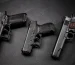 Tipos de pistolas: modelos full-size, compacta e 1911 de aço lado a lado sobre ardósia